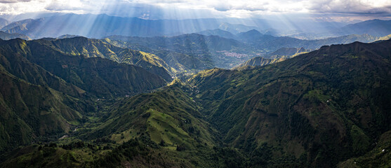 Dramatic aerial drone view of the lush green Andean mountain valleys near Vilcabamba, Loja Province, Ecuador, with spectacular god rays of sunlight breaking through dramatic clouds, illuminating the l © Michael