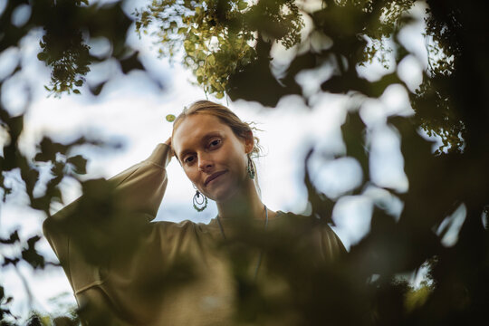 Woman framed by leaves with calm expression outdoors