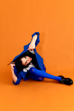 Woman posing in blue outfit on orange background