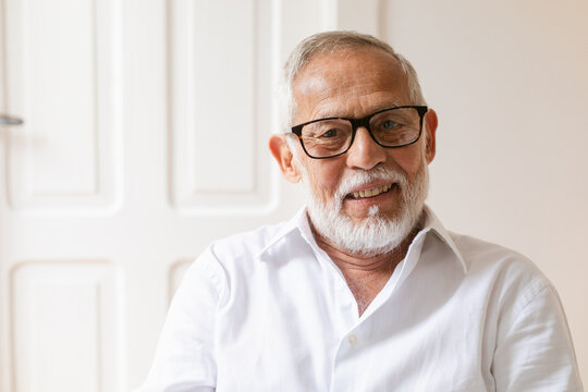 Elderly Man Smiling Warmly in a Light-Filled Indoor Setting