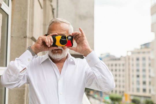 Smiling Man With Retro Camera in Urban Setting