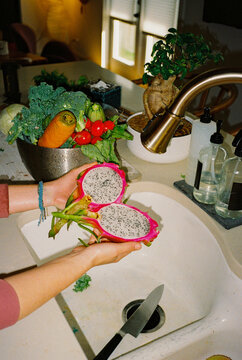 Woman washing dragonfruit in a sink after trip to the market, 