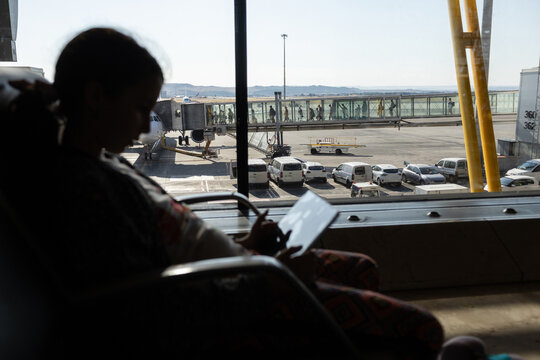 Silhouette of preteen girl using tablet in airport