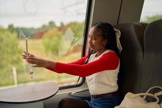 Young Woman Capturing Memories on a Train Journey Through Nature