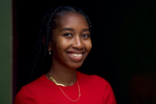Smiling Woman Wearing Red Sweater Stands in Doorway