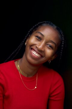 Young Woman Smiles Brightly While Posing Indoors in Vibrant Red Attire