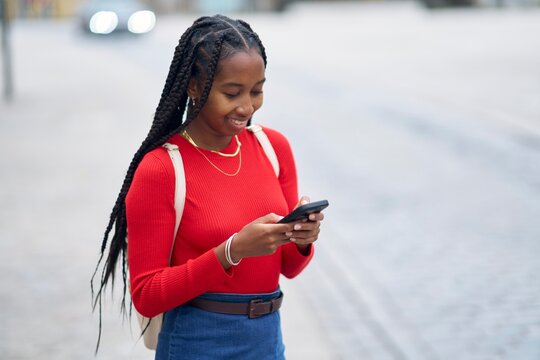 Young Woman Enjoying Her Phone on a City Street During the Day