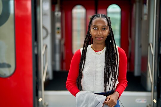 Young Woman With Braids Stands Inside a Train Boarding Area