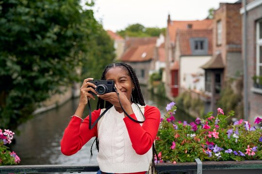 Smiling Woman Captures Memories With Camera in Scenic Canal Setting
