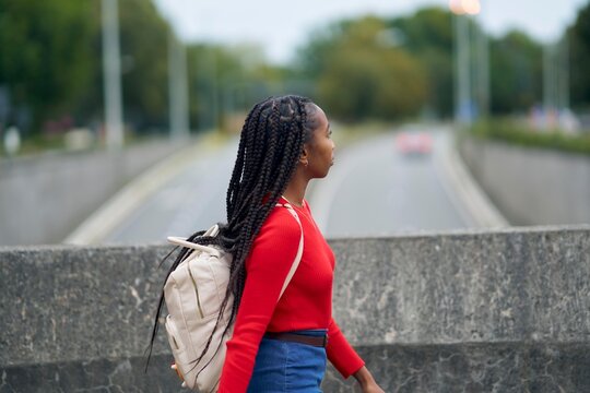 Young Woman Walking on Street With Backpack on a Cloudy Day