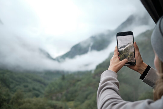 Women Capturing Scenic Mountain View From Train Window Using Smartphon