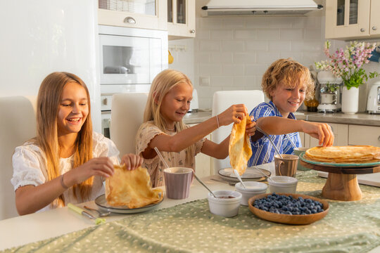 Children eat crepes in the kitchen