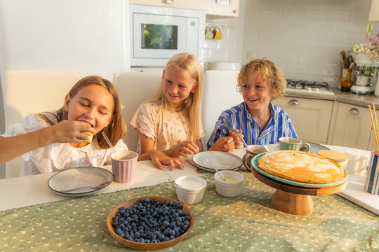 Children eat crepes in the kitchen