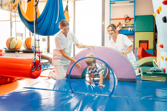Child crawling through tunnel during pediatric physical exercises
