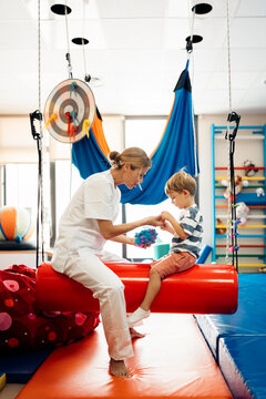 Physiotherapist helping child with psychomotor toy during therapy