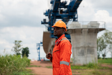 The survey team is operating a theodolite while referencing road construction plans. Civil engineers are taking measurements with surveying equipment at the construction site.