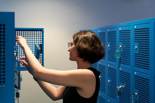 Woman Organizing Locker in a Bright, Modern Changing Room Space