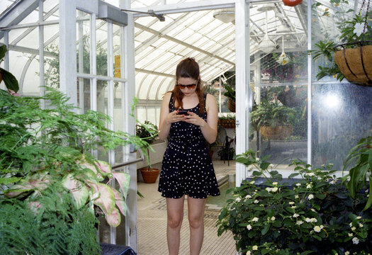 Woman in a polka dot dress checking her phone at a greenhouse