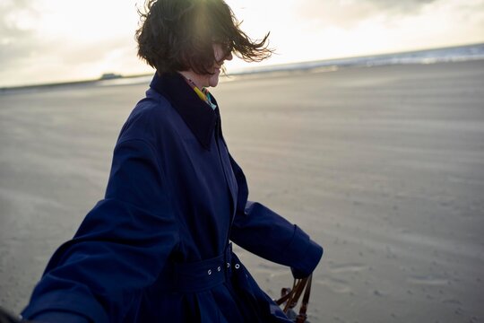 Woman Enjoying a Windy Day on the Beach During Sunset