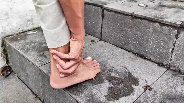 A man climbs the stairs holding his sore ankle.