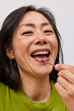 Beautiful asian woman applying brown lipstick