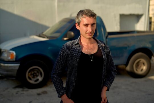 Person Standing Near a Blue Truck in a Sunny Outdoor Setting