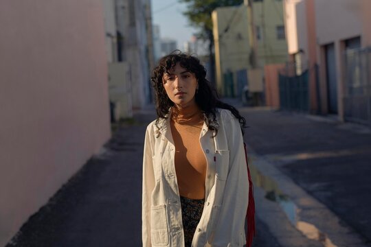 Young Woman Walks in a Narrow City Alley on a Sunny Day