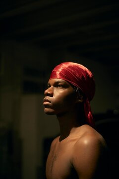 Young Man With Red Headscarf Poses in Low Light Setting