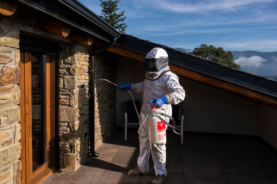 Professional fumigating a hidden wasp nest in the wall of a balcony