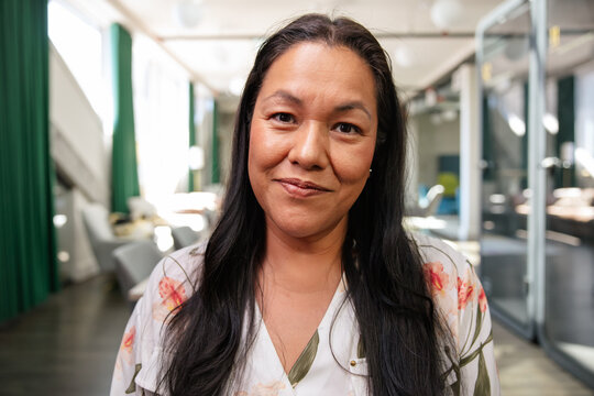 Confident woman in a modern office with a warm and friendly look