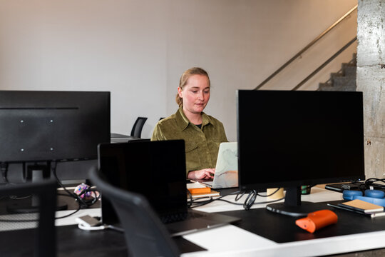 Woman Working at a Modern Office Desk With Multiple Computers