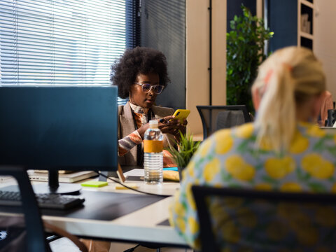 Woman Focused on Smartphone in Modern Office Workspace