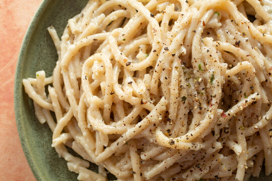 A top down view of a plate of dairy-free, gluten-free cacio e pepe bucatini.