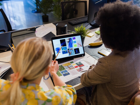 Colleagues discussing design on digital tablet screen 