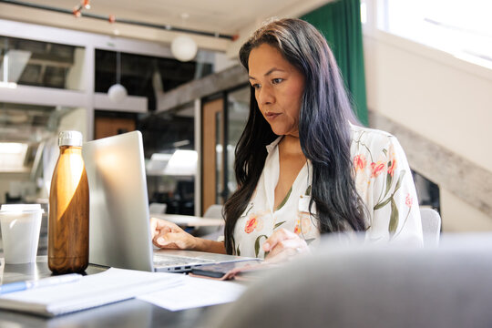 Professional woman working on a laptop in a modern office environment