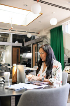 Professional woman using a laptop in a modern open-plan workspace
