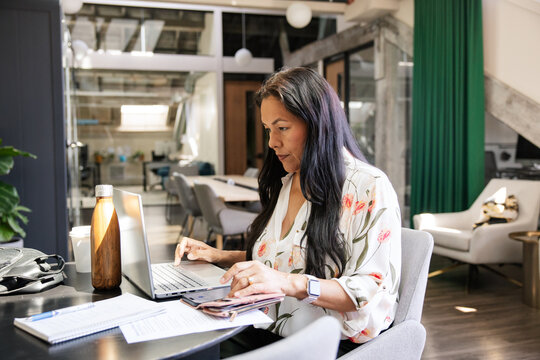 Focused woman working on laptop in open office workspace