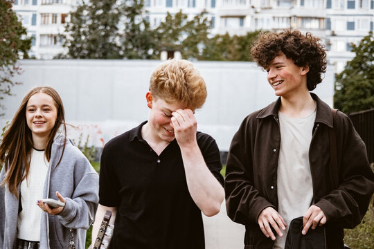 Three friends walk along a path in a park