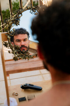 Reflection of young man clipping his hair in the mirror