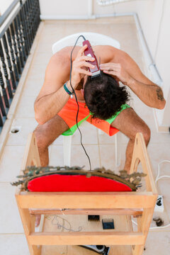 Young man clipping his hair at the balcony