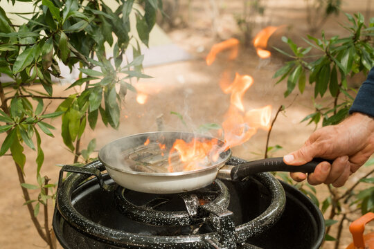 Cooking on a stove with flames and smoke outdoors in nature
