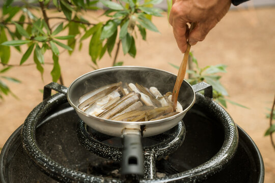 Cooking fresh clams over an outdoor fire in a rustic setting