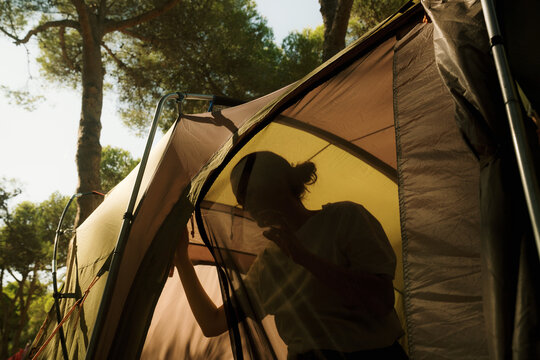 Woman inside a tent enjoying nature in the morning light