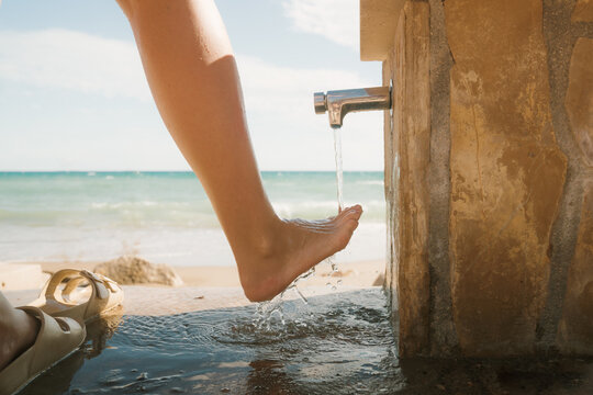 Foot dipping in beachside water spring under sunny sky