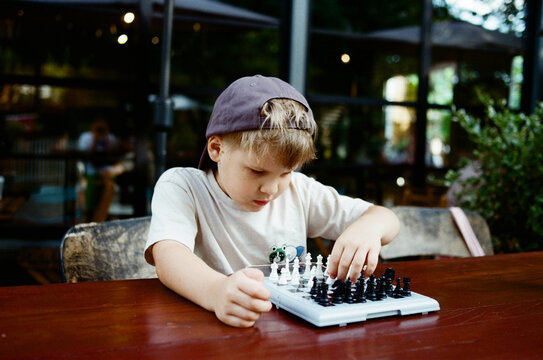 Child focused on playing chess outdoors