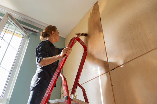 Woman painting wooden wall during home improvement project