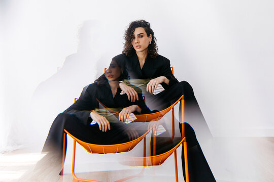 Queer person sitting in chair, double exposure effect