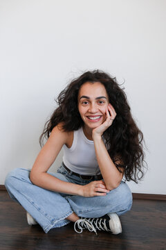 Woman Smiling While Sitting Casually on a Wooden Floor