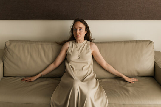 Serene Woman in Beige Dress on Beige Sofa