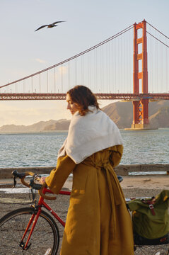 Woman in a Coat With Bicycle at Golden Gate Bridge at Sunset